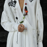 White shirt with black butterfly embroidery on a dark background