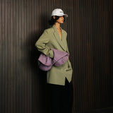 Person wearing a green coat and white cap against a dark wooden wall